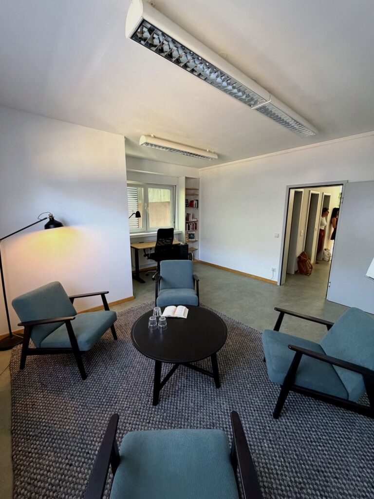 Blick in den Beratungsraum mit Sesselrunde und dem Arbeitsplatz am Fenster